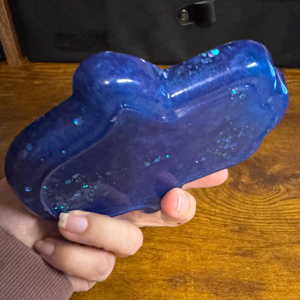 Hand holding a blue trinket dish on a wooden surface