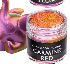 Jar of chameleon powder labeled 'Carmine Red' with a colorful container in the background.